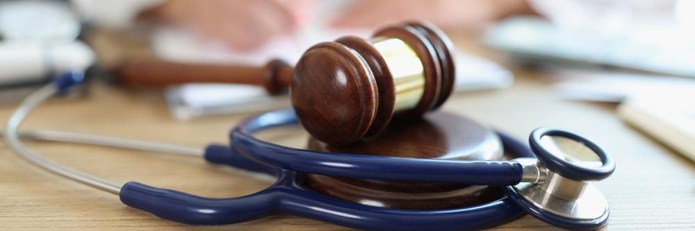 Close-up of judge hammer and doctor stethoscope on office desk. Medical malpractice, personal injury lawyer and healthcare legal aspects concept