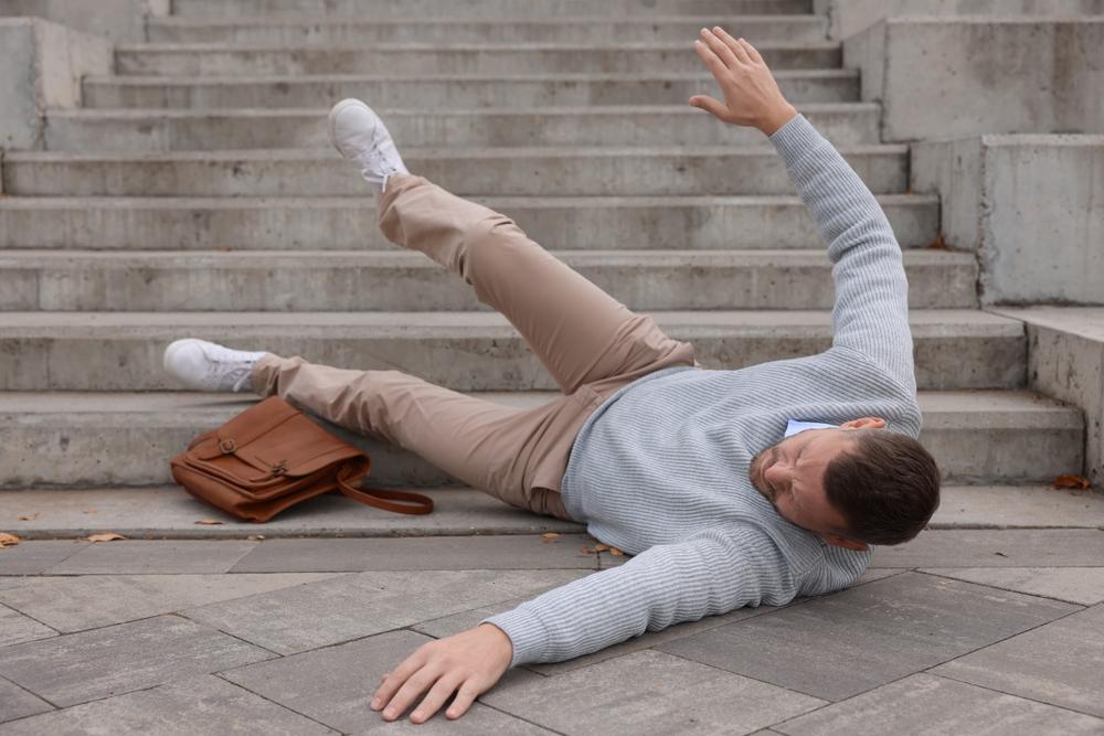Injured man on stairs outdoors after fall. Dangerous accident