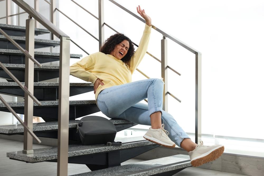 Injured woman on stairs in building after fall. Dangerous accident